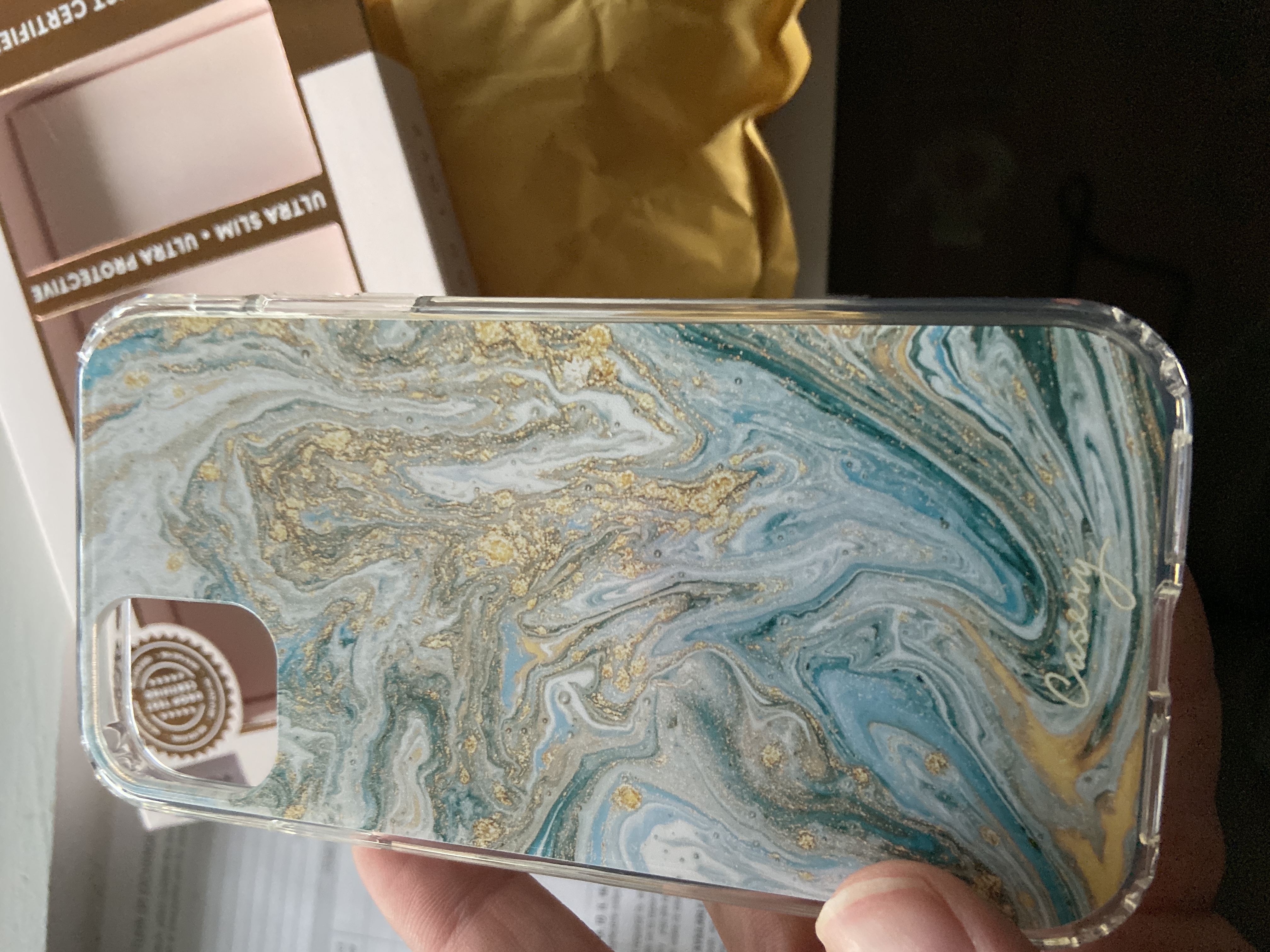 Casery phone case with blue marble pattern and gold accents held in hand